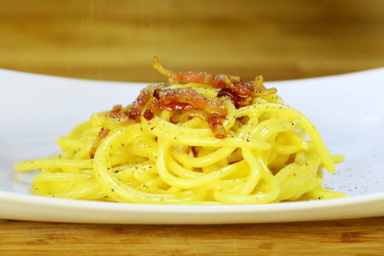 Spaghetti alla carbonara con pancetta croccante, bottiglia di vino sullo sfondo