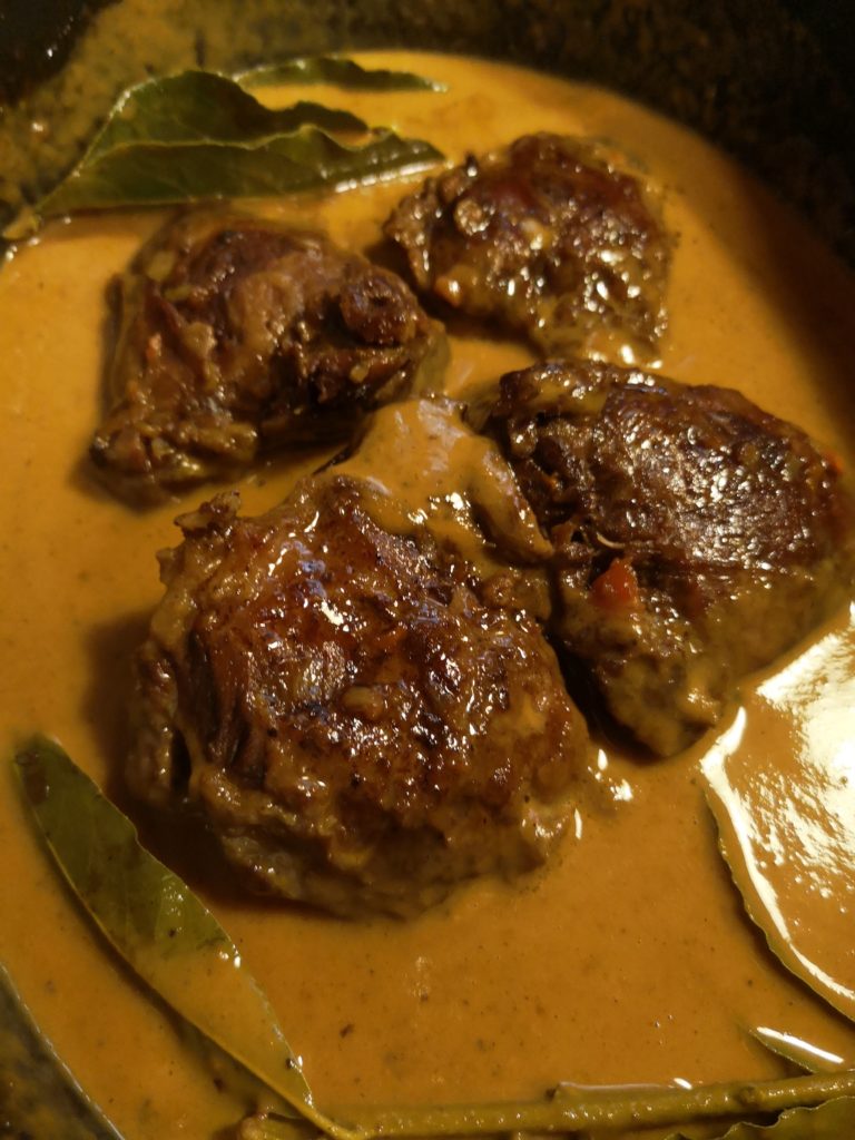 Guance di vitello brasate in salsa con foglie di alloro in una pentola