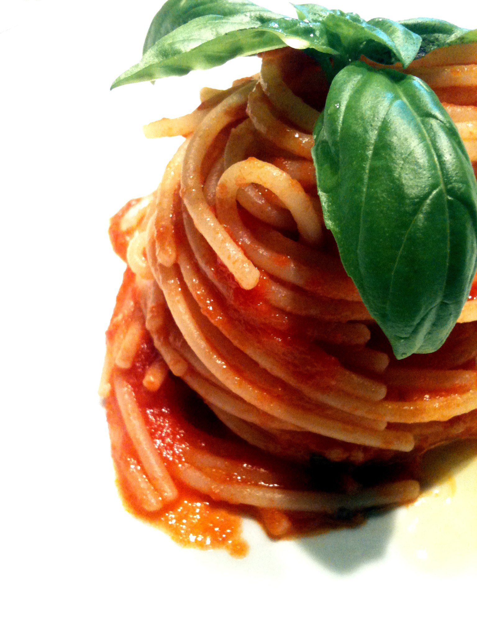 Spaghetti al pomodoro arrotolati con foglie di basilico sopra