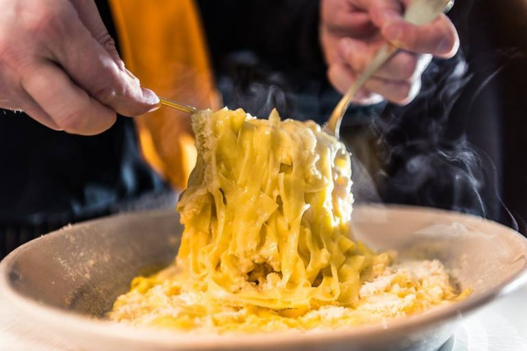 Mani mantecano fettuccine al burro e parmigiano con vapore che sale