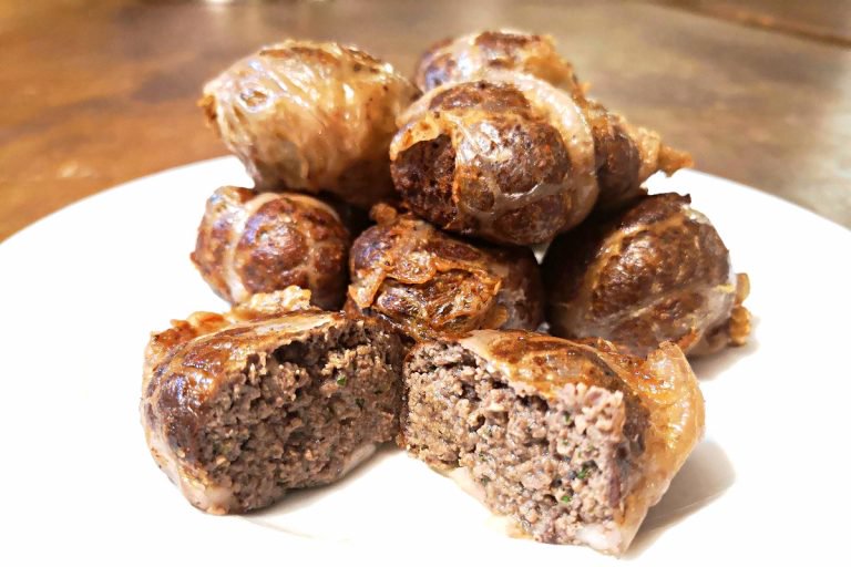 Involtini di carne macinata su un piatto, uno tagliato a metà