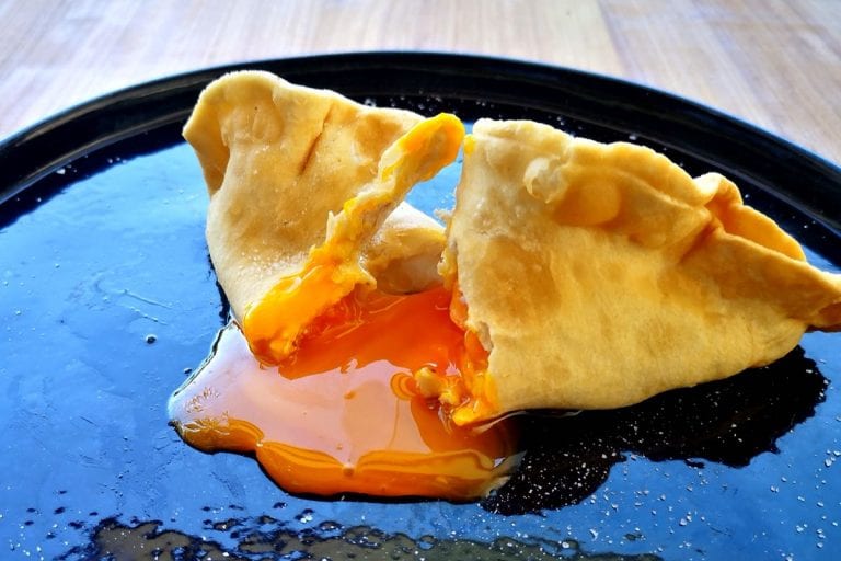 Raviolo tagliato con il tuorlo d'uovo che fuoriesce sul piatto