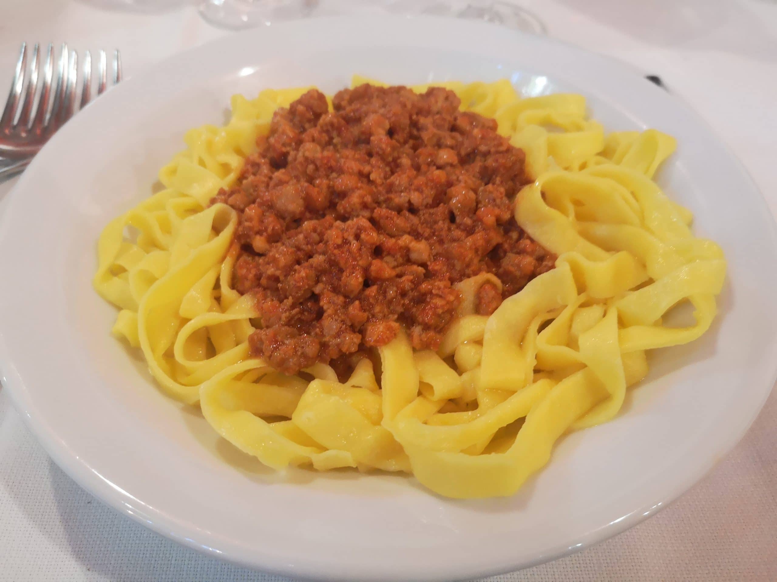Tagliatelle al ragù su un piatto bianco con la forchetta