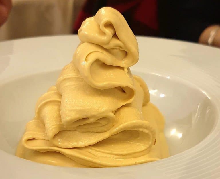 Sfoglia di pasta gialla arrotolata a fiore su un piatto bianco