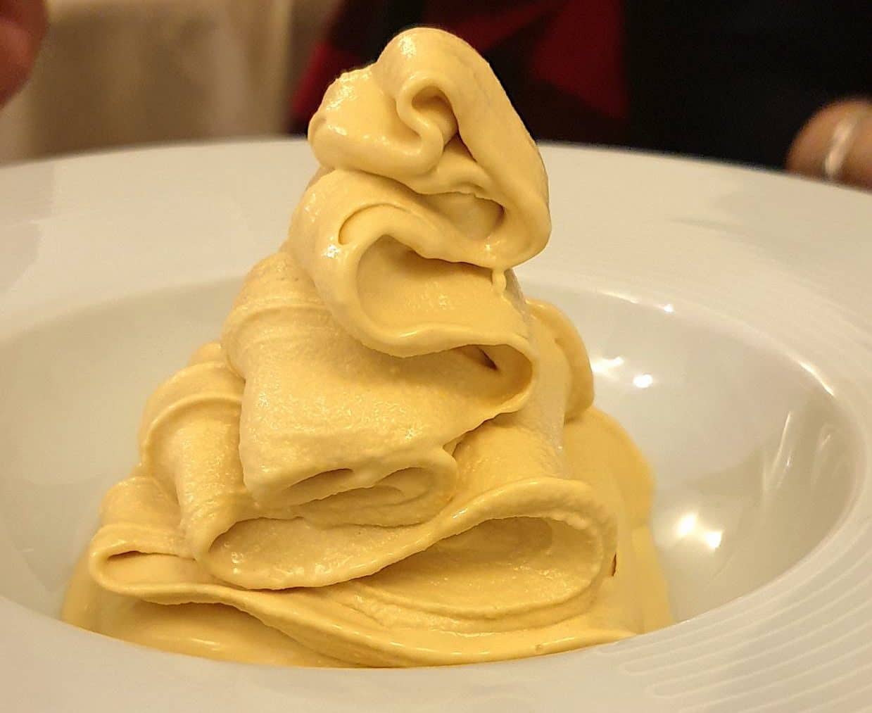 Sfoglia di pasta gialla arrotolata a fiore su un piatto bianco