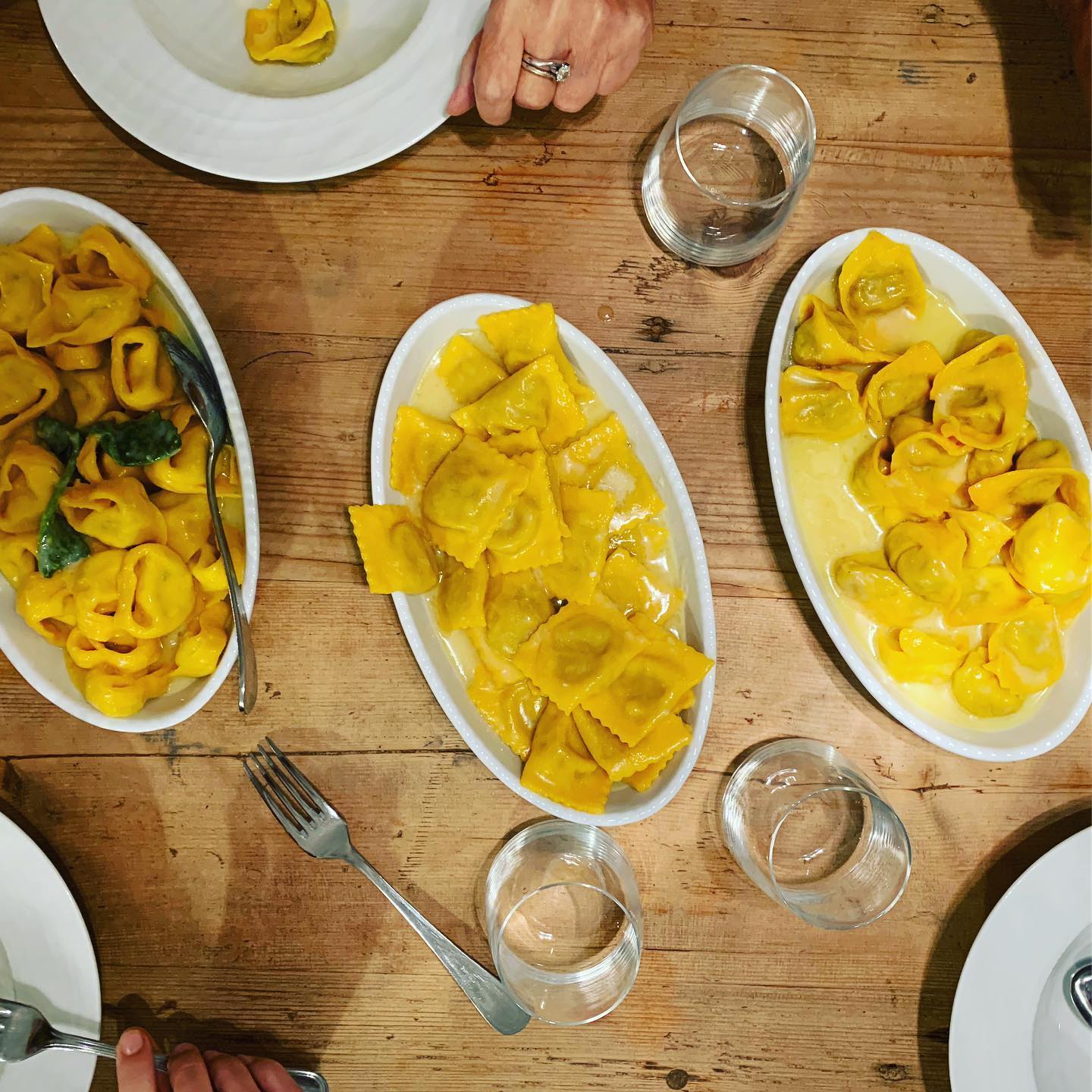 Tre piatti di pasta ripiena su un tavolo di legno