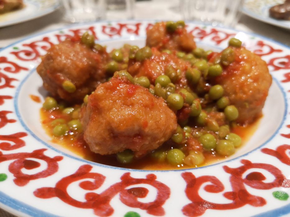 Polpette con piselli in salsa di pomodoro su un piatto decorato